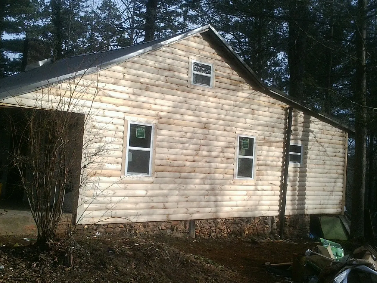 New log siding and dark metal roofing on a gable end in Caledonia